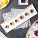 A rectangular white porcelain platter with desserts on a table.