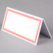 A white rectangular deli tent sign with a red checkered border.