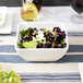 A bowl of salad with blueberries and cheese in a white bowl.