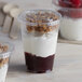 A narrow plastic parfait cup filled with yogurt, granola, and raspberries with a flat lid on top.