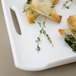 A white rectangular porcelain platter with spinach and cheese on it.