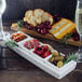 A 10 Strawberry Street Whittier rectangular porcelain tray with 4 dishes of cheese, crackers, and grapes on a table with a glass of wine.