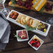 A white rectangular porcelain tray with dishes of bread and olives on a table.