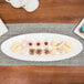 A white 10 Strawberry Street porcelain fish platter with cookies and cupcakes on a table.