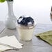 A Squat Parfait Cup with yogurt, blueberries, and oat flakes on a table.
