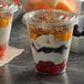A couple of plastic parfait cups with fruit and yogurt in them.