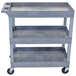 A Luxor grey plastic utility cart with three shelves and wheels.