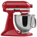 A red KitchenAid mixer with a stainless steel bowl.
