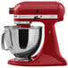 A red KitchenAid tilt head countertop mixer with a stainless steel bowl.