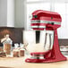 A red KitchenAid Artisan mixer sits on a counter with a bowl.