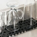 San Jamar black interlocking bar mat strips on a counter with a clear glass jug on top.