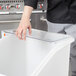 A person's hand reaching into a white Cambro lid on a white container.