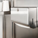 A Bobrick stainless steel surface-mounted paper towel dispenser on a wall.