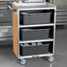 A Lakeside stainless steel utility cart with black plastic containers on the shelves.