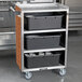 A Lakeside metal utility cart with black containers on metal shelves.