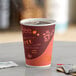 A close-up of a Choice 12 oz. Coffee Poly Paper Hot Cup full of coffee on a table.