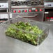 A clear Cambro flat lid on a container of lettuce.