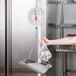 A woman using a Cardinal Detecto hanging scoop scale to weigh a bag of food.
