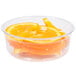 A Fabri-Kal clear plastic deli container filled with orange slices on a counter.