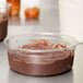 A Fabri-Kal clear plastic deli container filled with chocolate pudding on a counter.