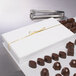 A large white candy box with a gold ribbon on top of chocolates.