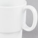 A close up of a Tuxton porcelain white mug with a handle.