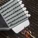 A Waring grill brush with a small piece of food on it.