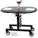A rectangular maple room service table with a stainless steel frame and black top with a vase of flowers on it.