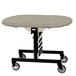 A Geneva mobile room service table with a beige top on a black metal frame with wheels.