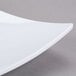 A close up of a white Thunder Group square melamine plate with a curved edge.