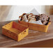American Metalcraft rectangular poplar wood basket filled with bread on a table in a bakery display.