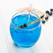 A blue drink in an Arcoroc Salto rocks glass with a straw and a small umbrella.