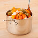 An American Metalcraft stainless steel pan with vegetables on a table.