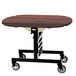 A Geneva round tri-fold room service table with a red maple finish on wheels.