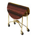 A Lakeside round wooden folding room service table with gold wheels.