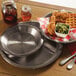A plate with chicken and waffles and a mini aluminum pie pan of honey on a table.