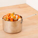 An American Metalcraft stainless steel pan of vegetables on a wood surface.