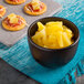 A bowl of pineapple tidbits with cheese and crackers on a table.