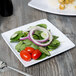 A Thunder Group Classic White square melamine plate with salad, tomatoes, and onions with a silver fork.