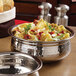 A close-up of a silver American Metalcraft stainless steel bowl filled with pasta and vegetables.