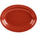 A close-up of a red oval Fiesta medium china platter with a rim.