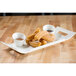 A white rectangular porcelain platter with churros and dipping sauce.