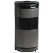 A black and silver cylinder with holes, containing a black Rubbermaid recycling container.