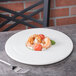 A 10 Strawberry Street Whittier white porcelain plate with shrimp and tomatoes on it.