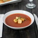 A white Arcoroc coupe bowl filled with tomato soup and croutons.