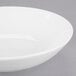 An Arcoroc white coupe bowl with a rim on a gray surface.