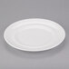 An Arcoroc white porcelain dinner plate with a rim on a gray surface.