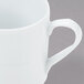 A close-up of a white Arcoroc stackable coffee mug with a handle.