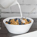 A 10 Strawberry Street Swing white porcelain cereal bowl filled with cereal and blueberries with milk being poured over it.
