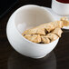 A white 10 Strawberry Street Whittier angled bowl filled with cookies on a table.